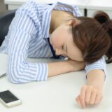 会社のデスクで突っ伏して寝る女性