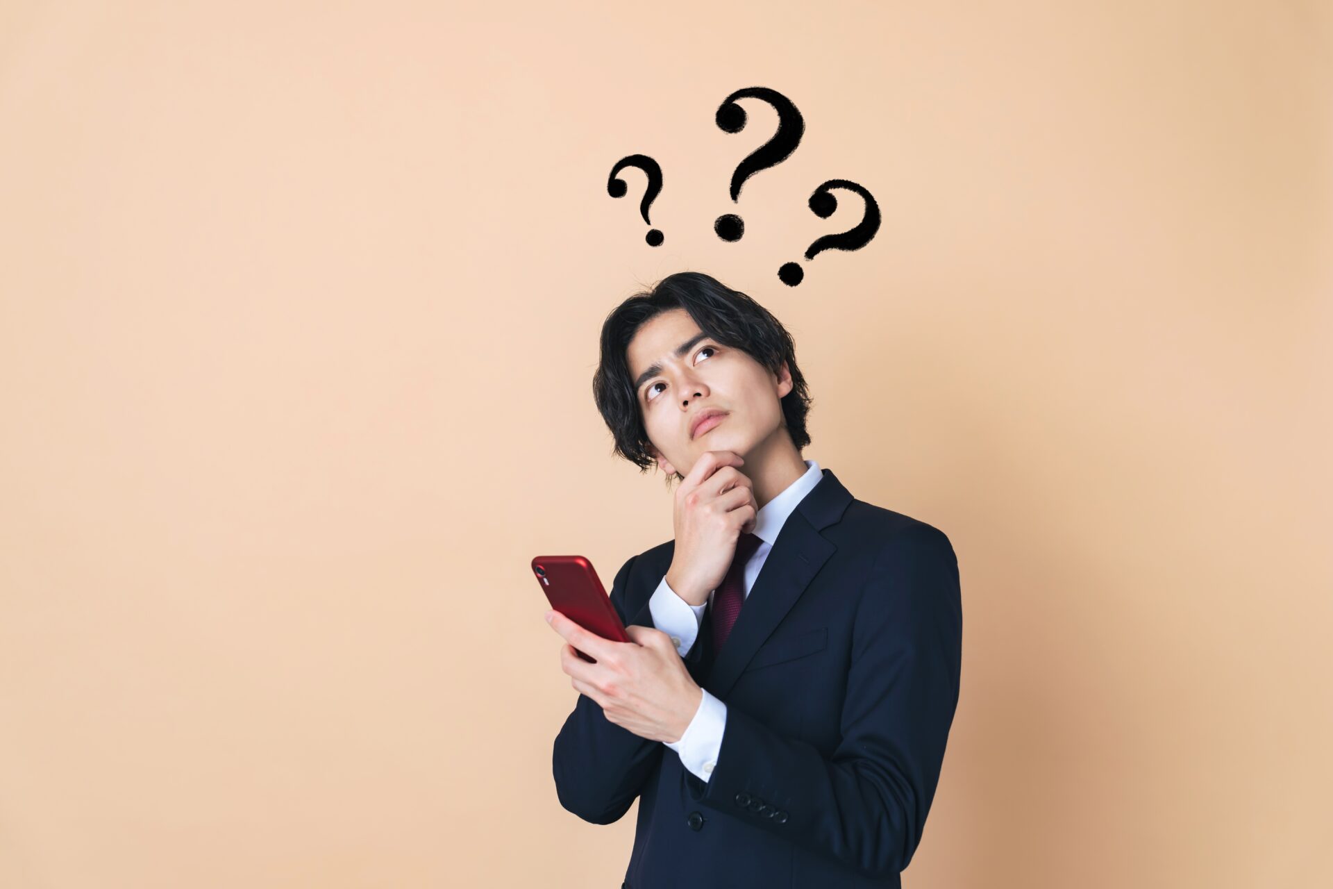 スマートフォンで求人情報を調べながら考えている若い日本人の男性